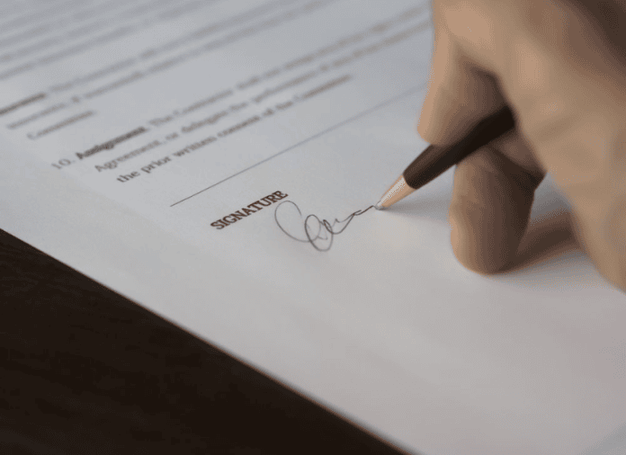 Persona firmando un contrato de trabajo, símbolo del descenso del paro en España en junio de 2026